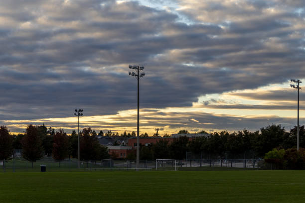 istock Sunset over soccer field - dramatic clouds - silhouette of stadium lights - trees behind 2160336565