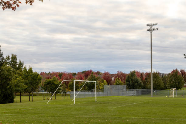istock Soccer field in autumn - goalposts at forefront - vibrant fall foliage in background - overcast sky above - serene and spacious 2160336566