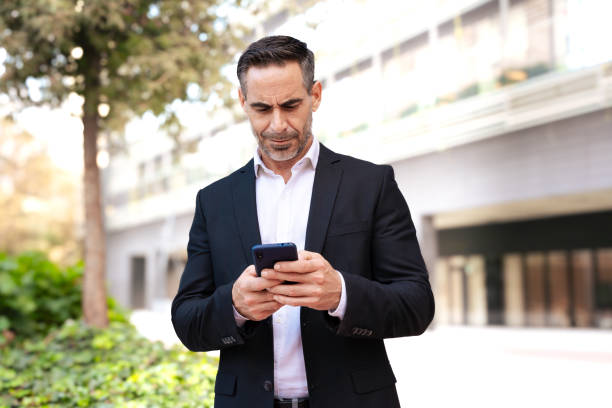 istock Businessman using an app on his smartphone and standing outdoors 2160345219