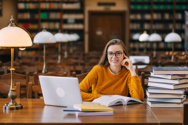 istock . the student studies in the school library, uses a laptop, and searches for information on the Internet or in books 2160347488