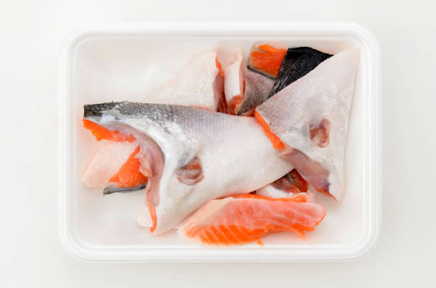 istock Silver salmon scraps in foam food tray on white background. 2160354926