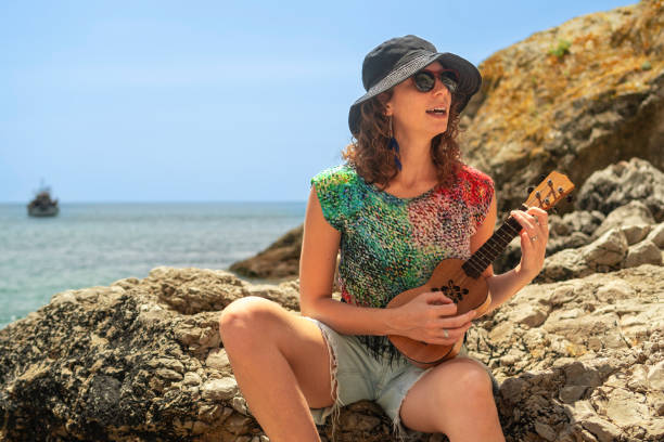 istock Woman on the beach with stringed musical instrument 2160355369