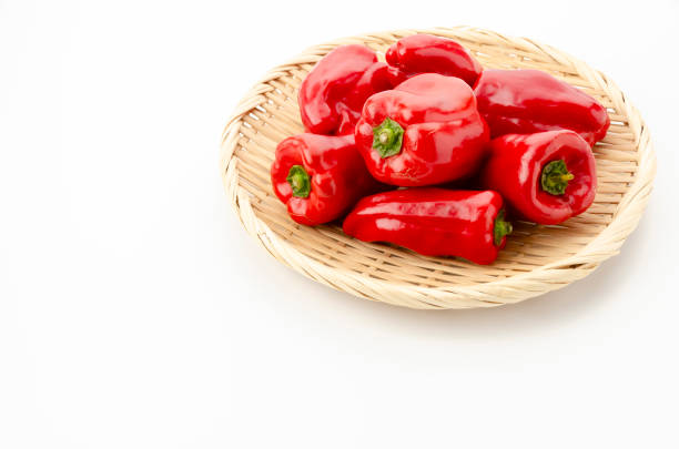 fresh red bell pepper on bamboo strainer on white background
