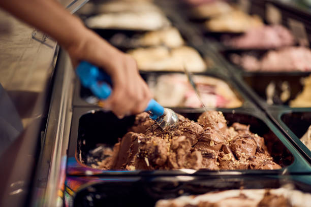 istock Chocolate ice cream in a container in a glass case, using a scoop of it. 2160359826