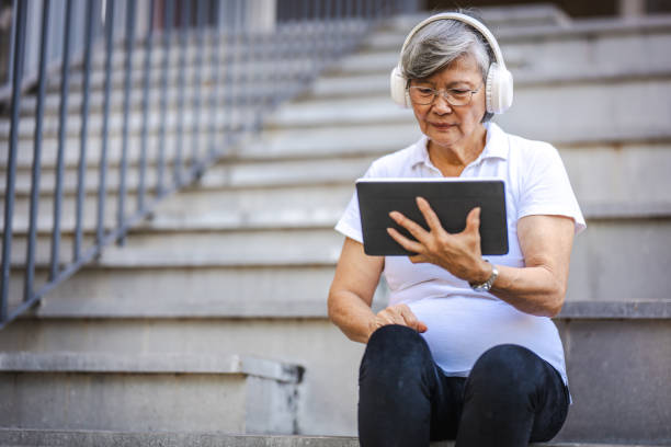 istock Tech-Enhanced Serenity: Senior Asian Woman's Park Playlist 2160367346