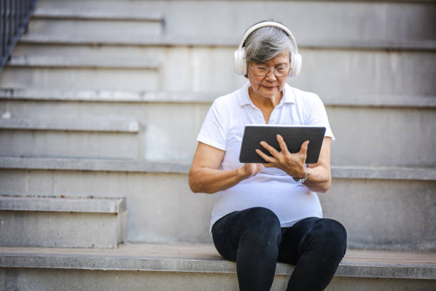 istock Music in Nature: Senior Asian Woman's Digital Park Retreat 2160367349