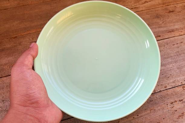istock hand holding empty plate on wooden texture background 2160372776