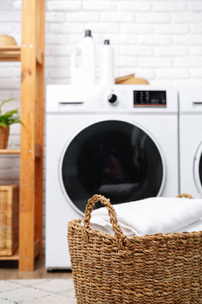 istock Laundry Basket With White Towels Near Modern Washers In A Modern Home 2160384847