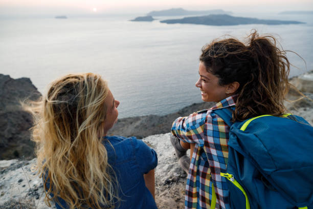 istock Happy female hikers talking on a break above the sea. 2160391696