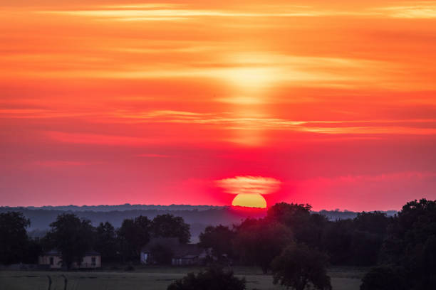 A beautiful red sun disc rising above the horizon. Natural scenery of summer in rural Latvia, Northern Europe.