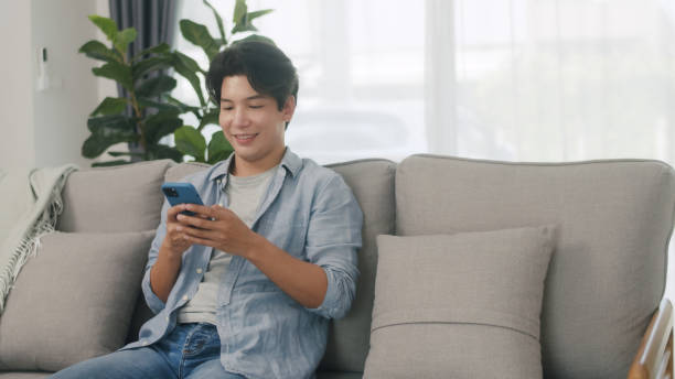 istock Happy Young Man Texting on Smartphone at Home. 2160397999