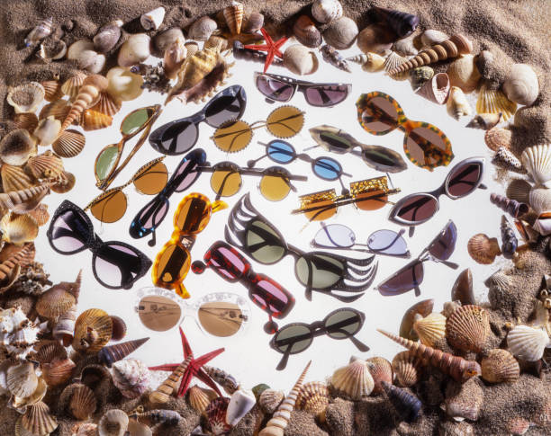 Trendy eyeglasses set. Summer vacation accessory among beach sand and shells. Studio shot.