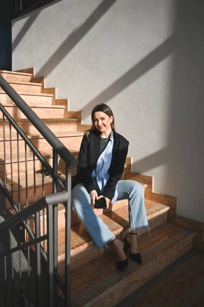 istock Cheerful woman sitting on stairs. 2160414363