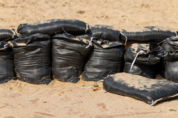 a pile of black bags on a sandy beach
