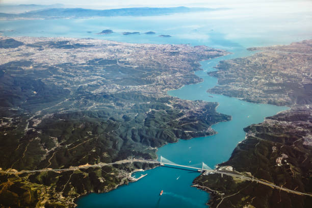 A stunning aerial view of Istanbul, Turkey, capturing the mesmerizing Bosphorus Strait that separates the city's European and Asian sides. The image showcases Istanbul's unique blend of ancient architecture and modern skyline, with iconic landmarks such as the Hagia Sophia, the Blue Mosque, and the Galata Tower visible. The Bosphorus is dotted with boats and ships, emphasizing the city's vibrant maritime activity. The azure waters of the strait beautifully contrast with the urban landscape, while the sprawling cityscape illustrates the city's rich cultural heritage and its strategic importance as a bridge between two continents.