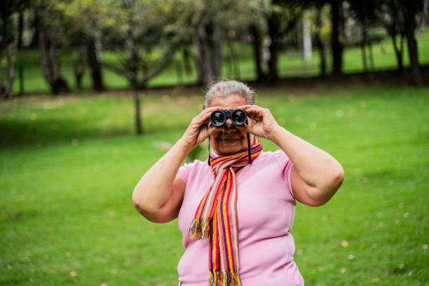 istock Senior woman looking through binoculars outdoors 2160421381