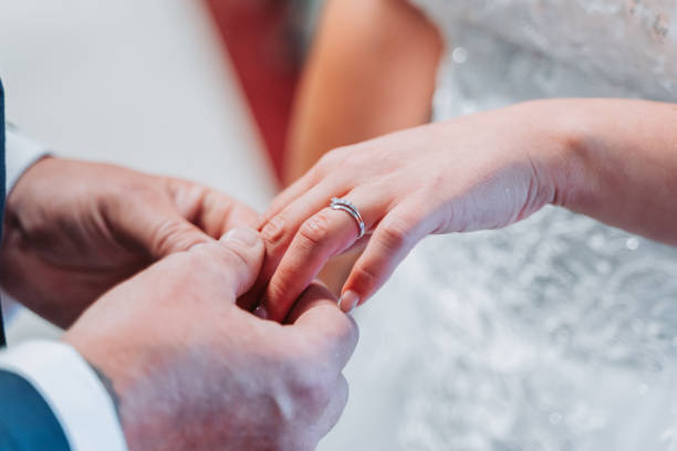 istock groom placing wedding ring on bride 2160421640