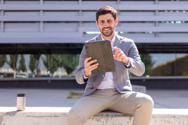 istock Businessman sitting outside office building using digital tablet 2160421936