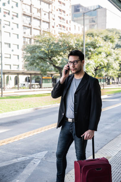 istock Mid adult man talking on phone on a bus stop 2160422333