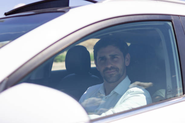 istock Businessman driving car looking away from camera 2160423222