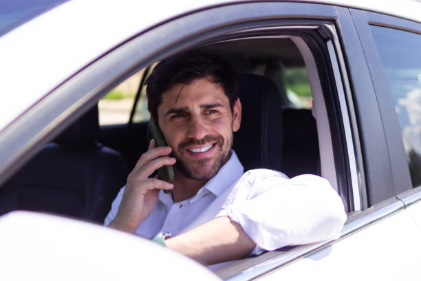 istock Businessman smiling while talking on the phone in his car 2160423404