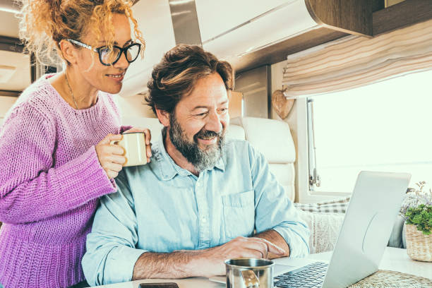 istock Happy couple man and woman working and using together a laptop computer inside a camper van planning holiday vacation destination and living vanlife lifestyle in freedom. People travel and tourism 2160423455