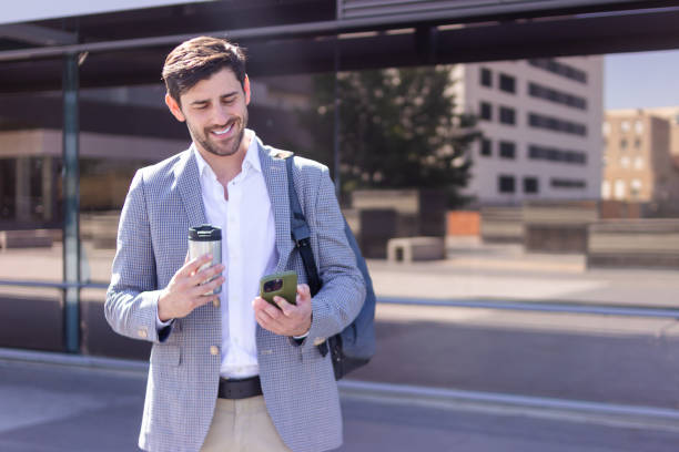 istock Businessman smiling while reading a text message and holding a coffee thermos 2160423788