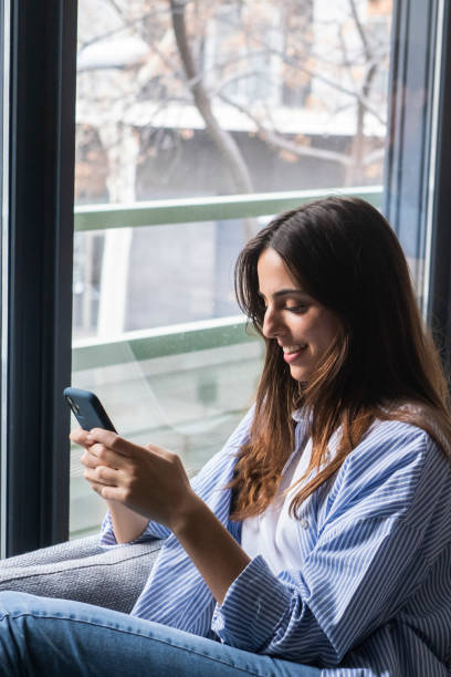 istock Millennial couple using modern devices sitting on couch and desk separated. Modern people working at home and using technology in indoor leisure activity. Man and woman writing on phone and laptop 2160423931