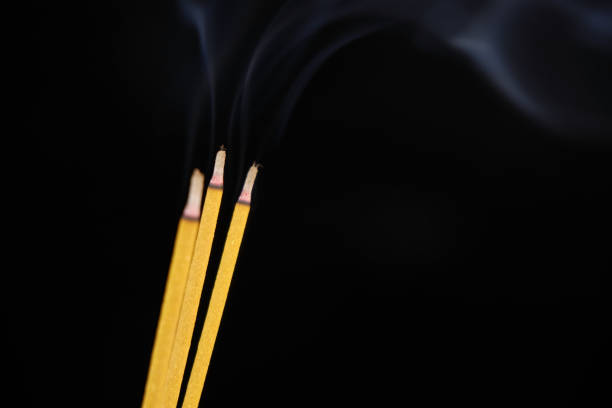 istock Yellow incense sticks burning on black 2160426522