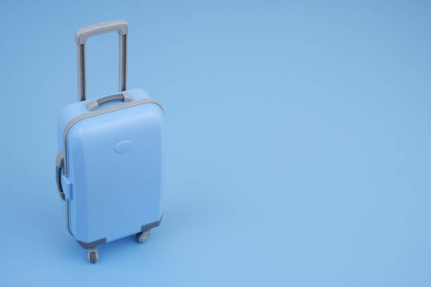 istock Shopping cart with suitcase on blue background close up. 2160427443