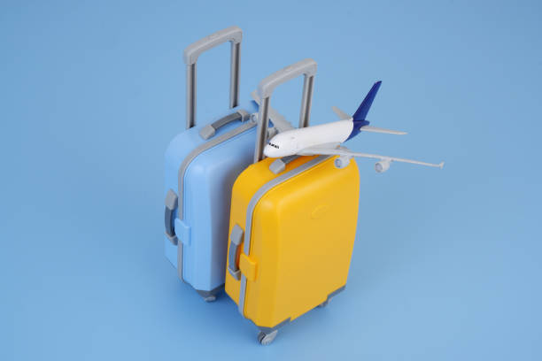 istock Airplane model on orange and blue suitcases on blue background. 2160427447