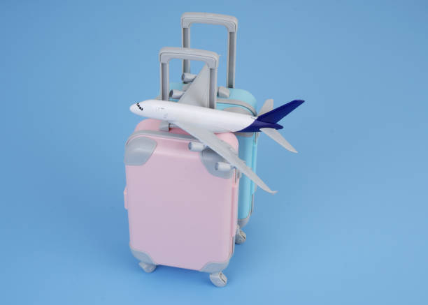 istock Airplane on pink and blue suitcases on blue background. 2160427766