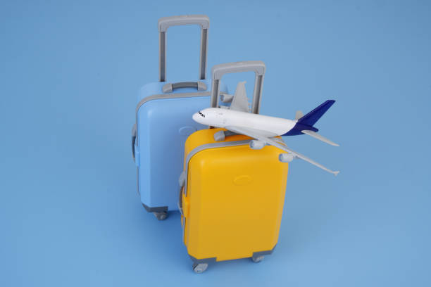 istock Airplane model on orange and blue suitcases on blue background. 2160427767