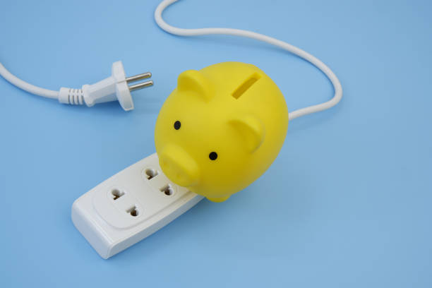 istock Piggy bank on electric sockets on blue. 2160429286