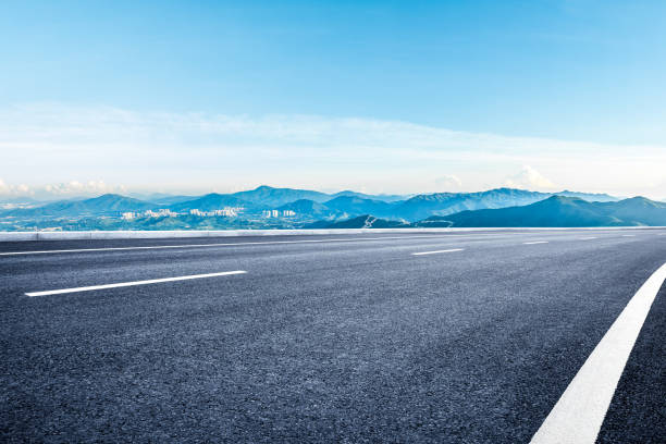 istock Empty asphalt road and mountains with city skyline 2160432210