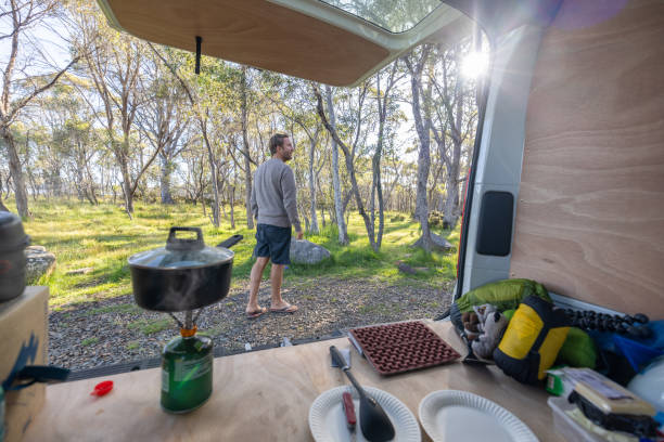 istock Man Standing Outside Camper Van with Cooking Setup 2160435486