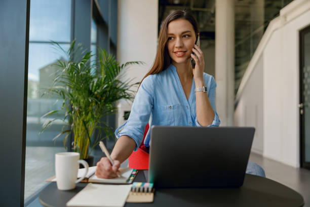 istock A businesswoman is in her professional workspace, multitasking by taking notes on a call 2160437793