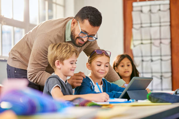 istock Elementary students working on digital tablet with the help of the teacher 2160437911