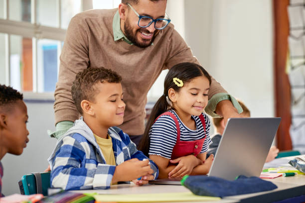 istock Primary students using laptop with male teacher 2160437990