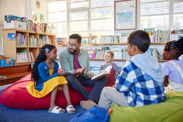 Teacher reading book to his little students in a library