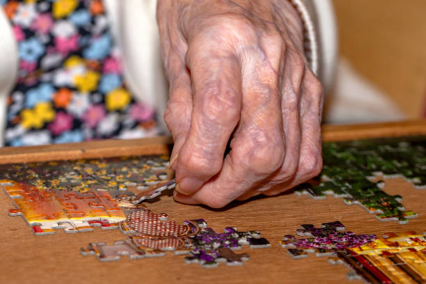 istock Elderly Person's Hand Placing Puzzle Piece 2160440309