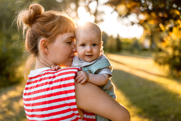 Hug for a cute little baby boy Mother hugging and kissing her cute little baby boy on a meadow in sunset. mom and baby eye contact stock pictures, royalty-free photos & images