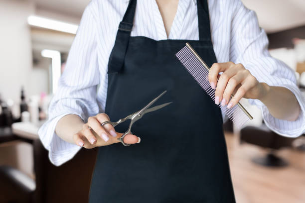 istock Barber in uniform holding scissors and comb. 2160442186
