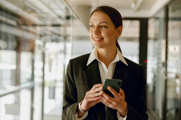 istock Smiling businesswoman in modern office confidently using a smartphone to communicate and work 2160442427