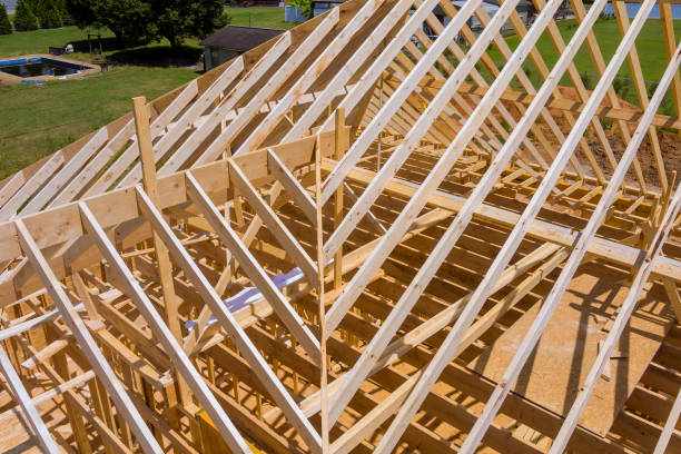 istock Installation of timber roofing truss frames by a building under construction roof 2160445149
