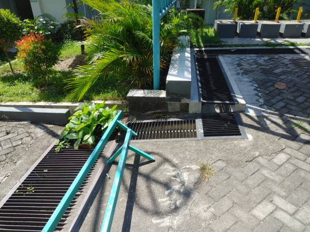New rainwater grate on the road or sidewalk, installation of open and close system. rainwater grate on the road or sidewalk, installation of open and close system. City waste disposal system to drain water during heavy rain. Equipped with long iron waste barriers stopcock stock pictures, royalty-free photos & images