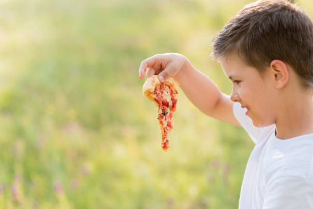 istock Cute child eating pizza in nature in summer 2160447709