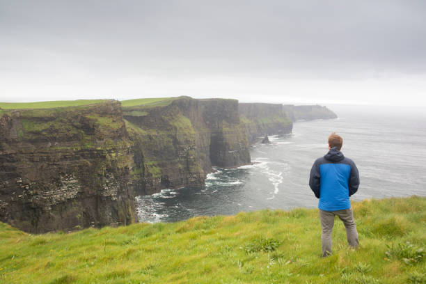 istock Man looks towards rugged coastline on rainy day 2160450197