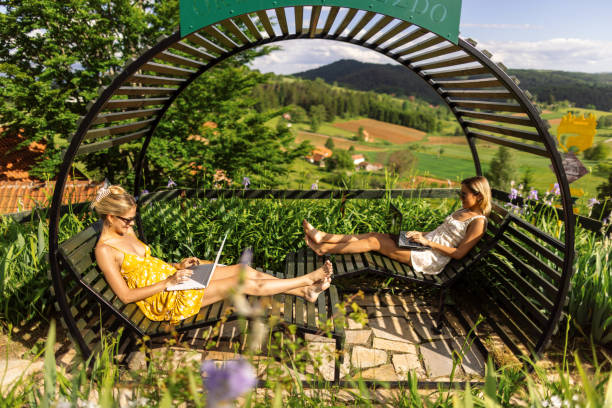 istock Two attractive women working on their laptops in a beautiful countryside environment 2160454731