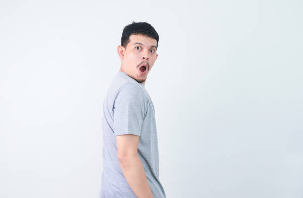 istock Asian young man grey shirt feels amazed turn back to looking isolated 2160457617